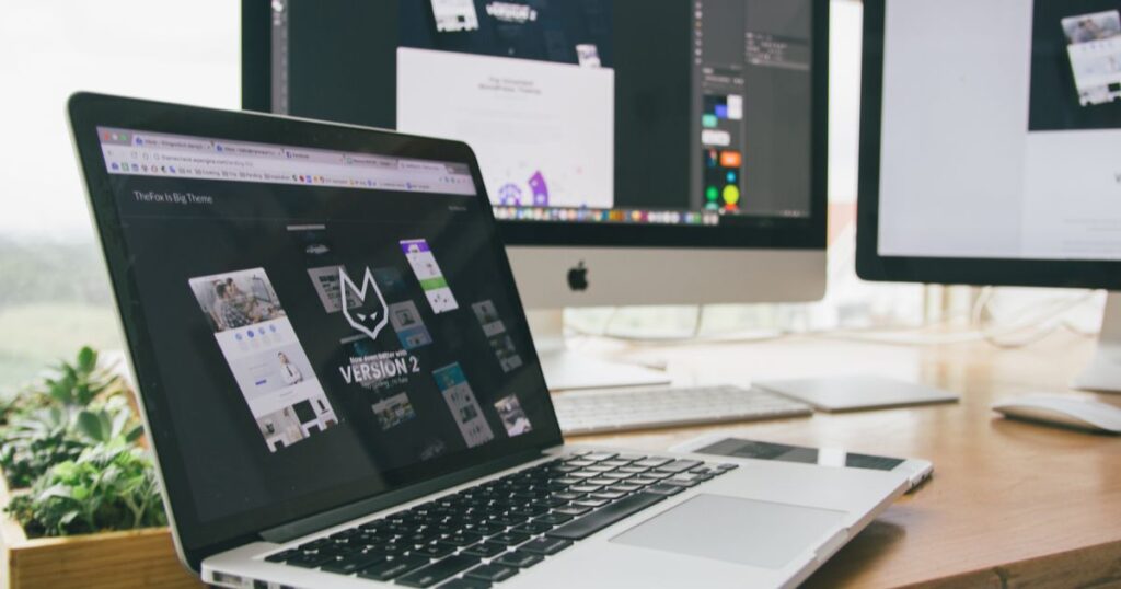 SEO for website redesign: designer's workspace with a laptop and monitors showing a new site design