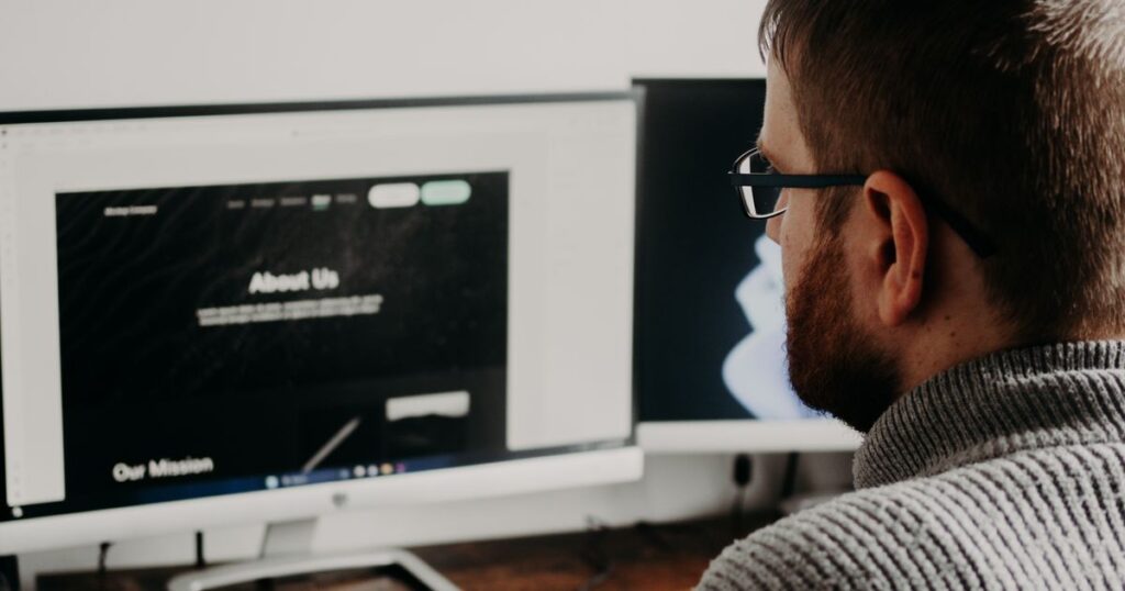 Web designer and SEO: web designer working on a website across two monitors