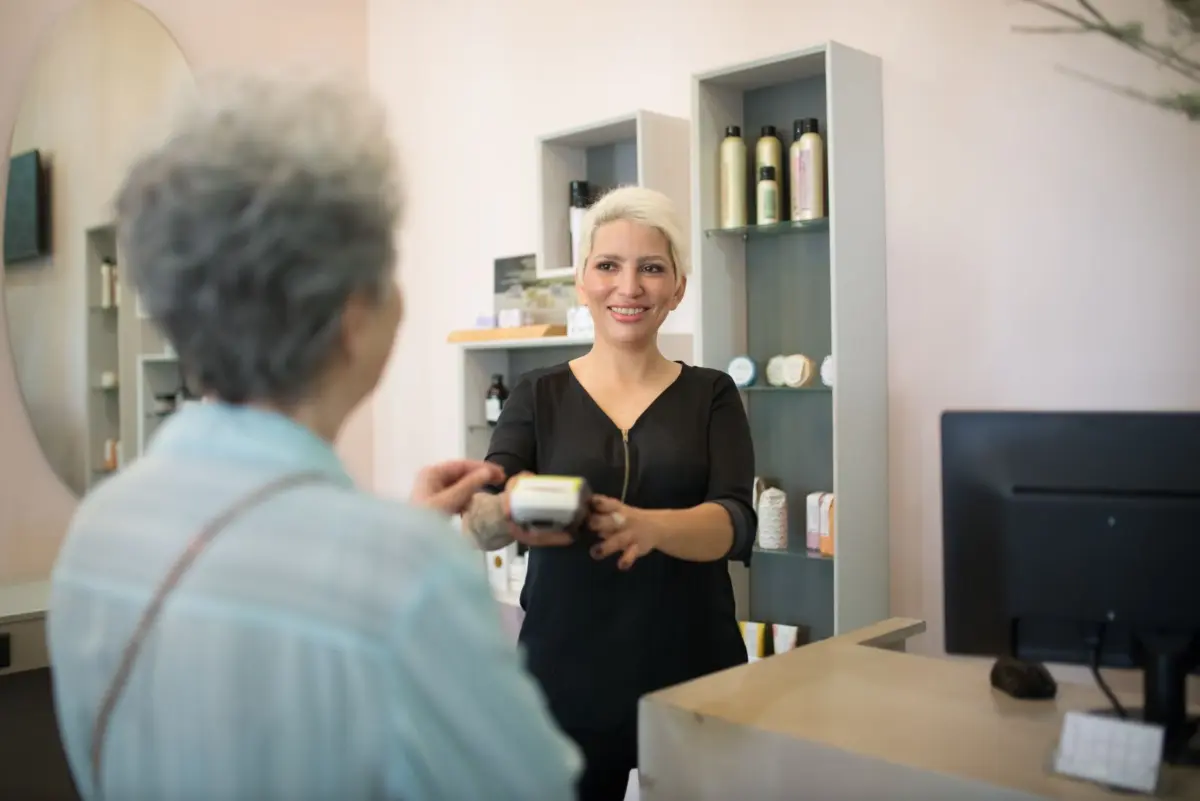 Salon owner at the checkout desk with a client, the right moment to ask for a review