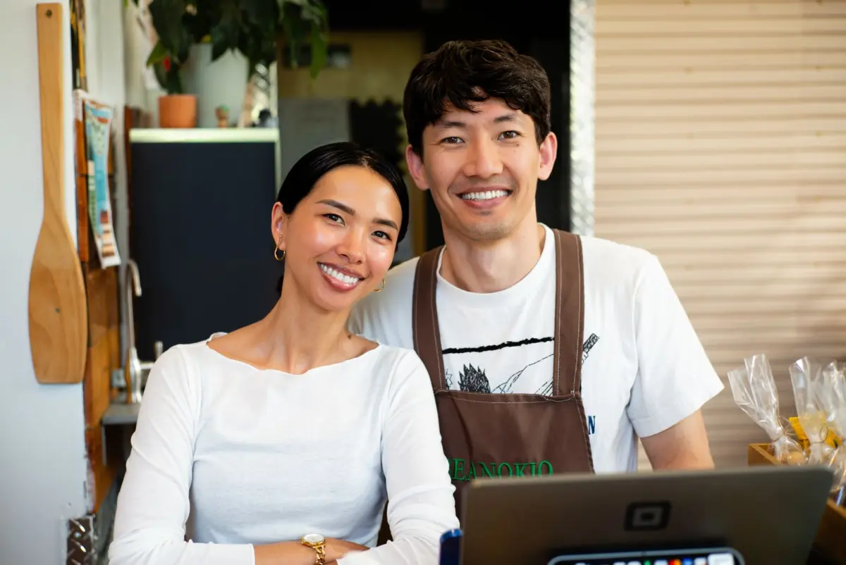 Two smiling cafe owners behind the counter ready to ask happy customers for reviews