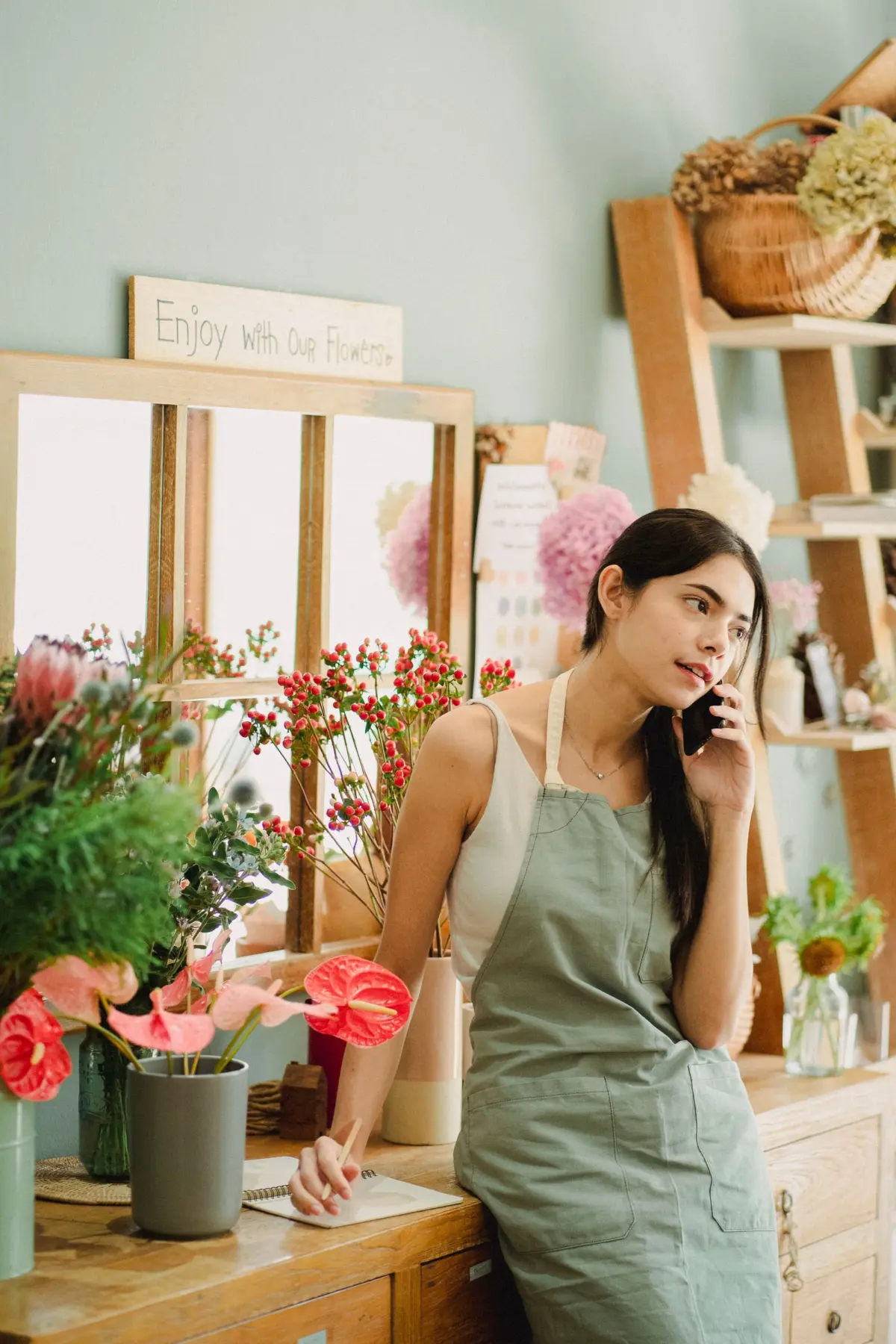 Florist in her shop answering a phone call and writing down a code