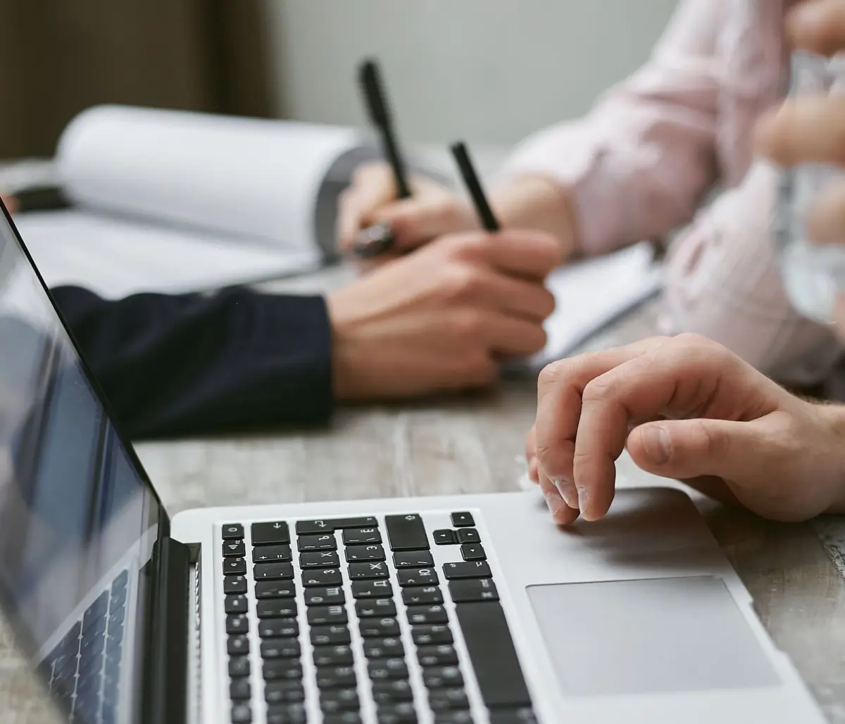 Web designer and client reviewing website plans on paper beside a laptop during a meeting