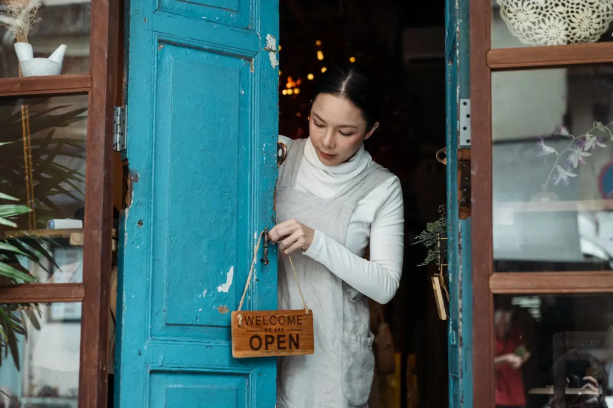 Shop owner hanging a welcome open sign on the door of her new premises